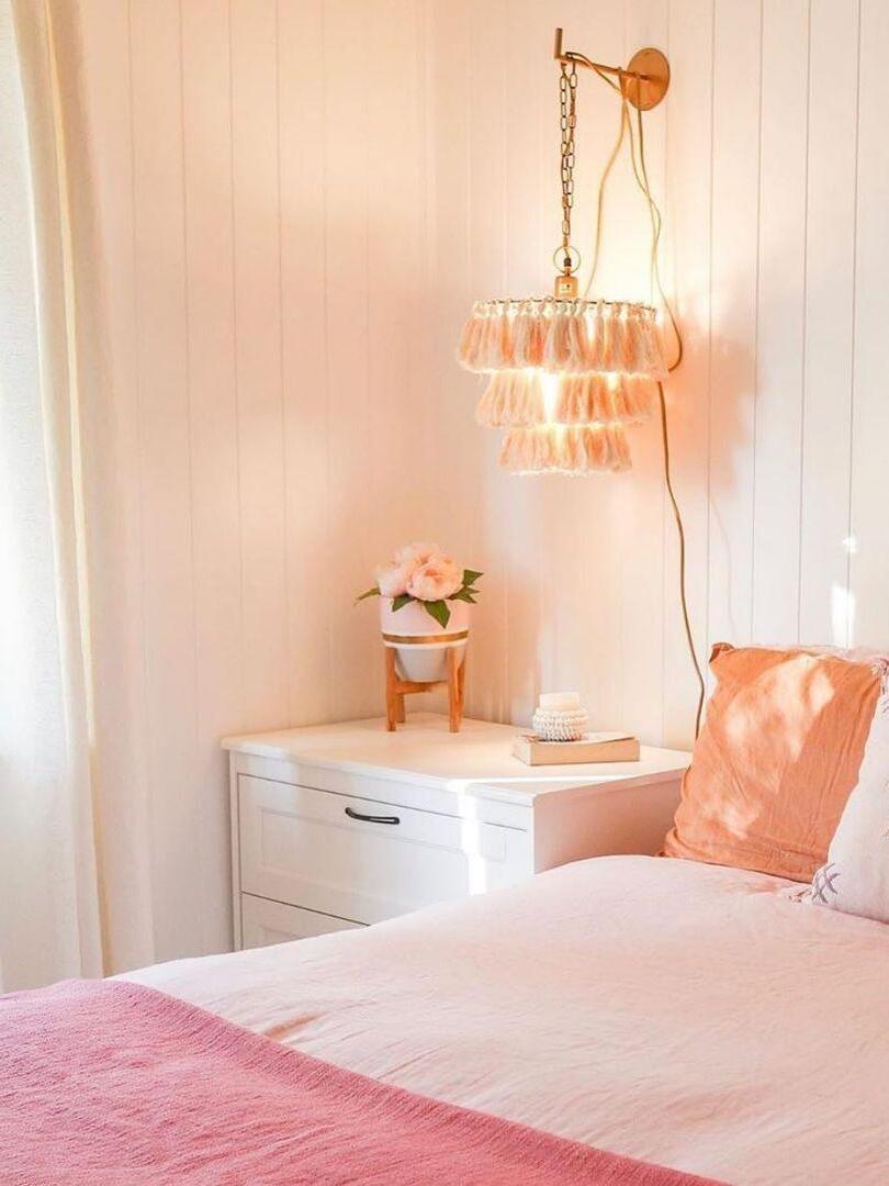 Pink tassel wall light beside a bedside cabinet