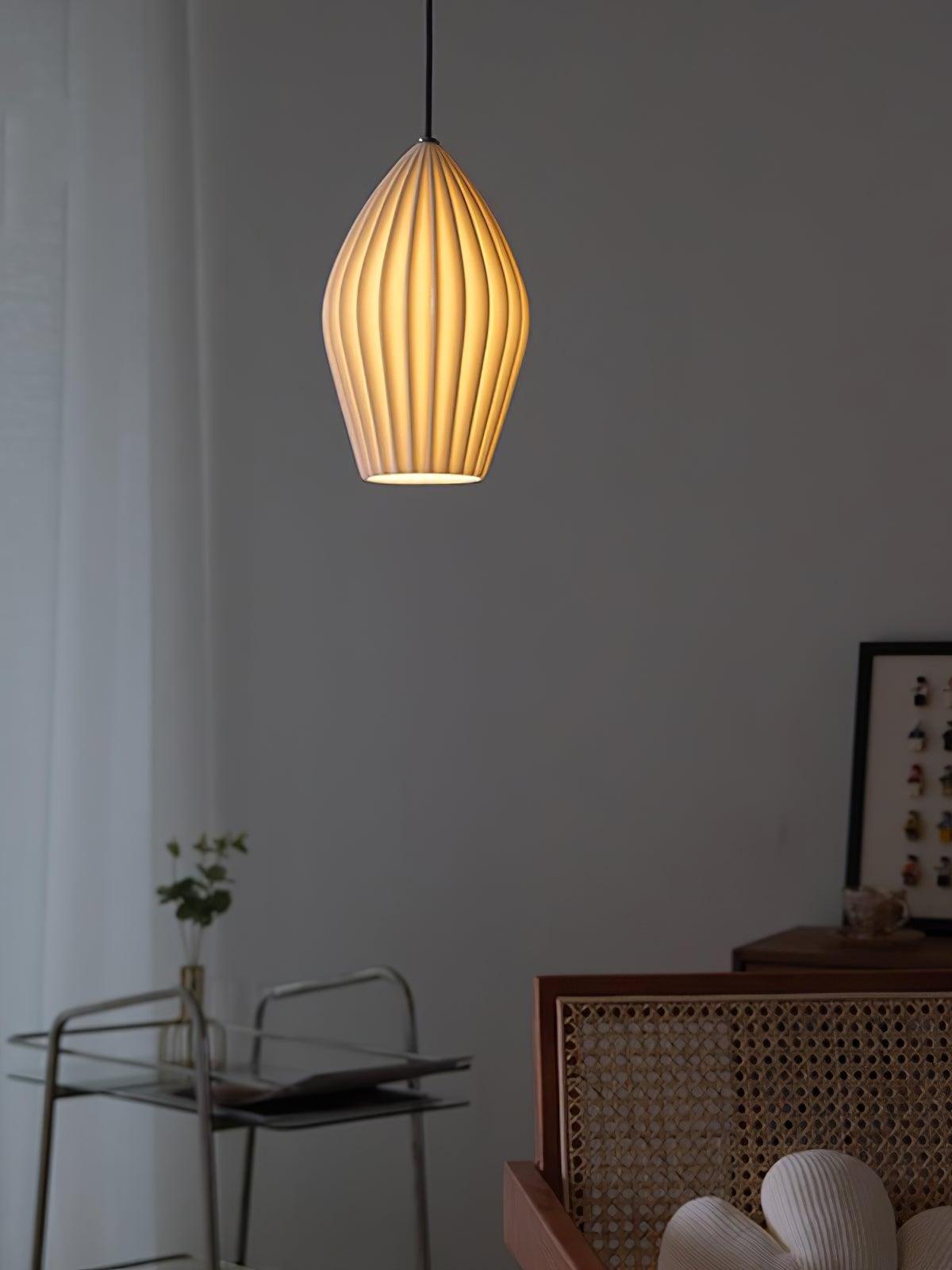 Single illuminated ribbed ceramic shade above a small table against a grey wall