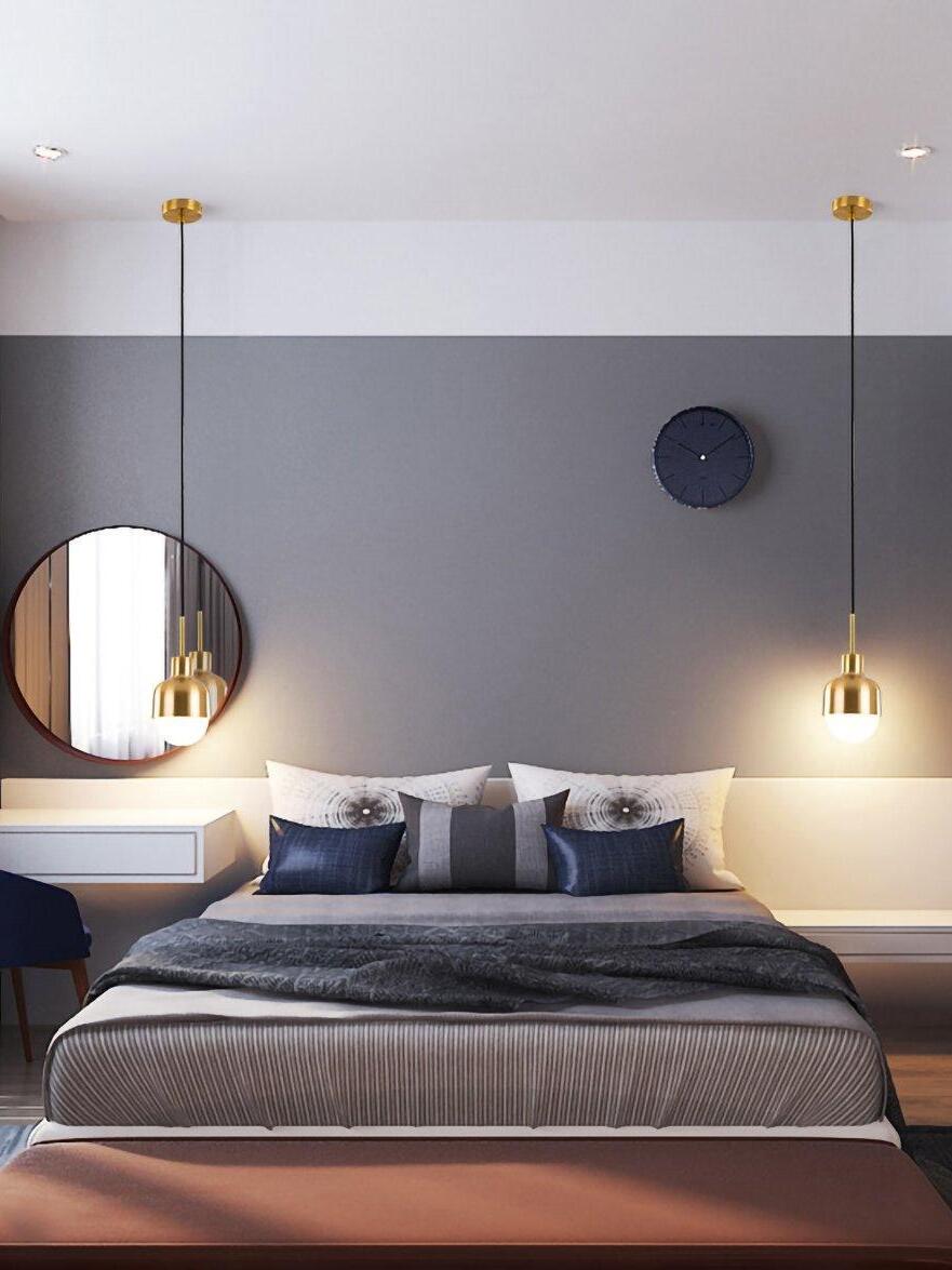 Two lit Niku bedside pendants on individual canopies beside a bed, round mirror and wall clock