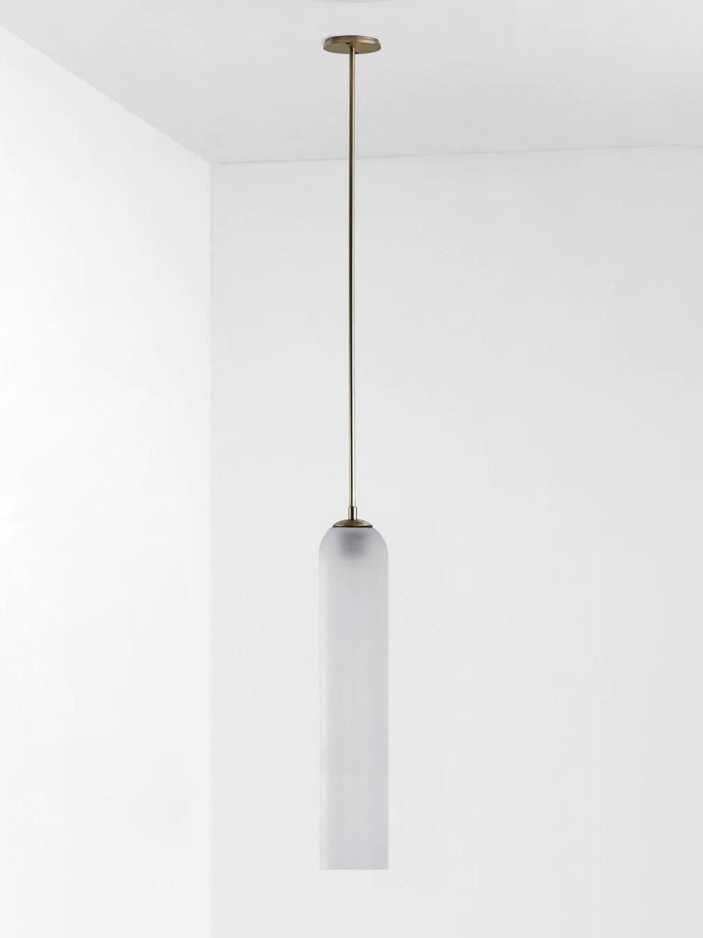 Frosted white glass Long Tube pendant with gold-toned straight rod and round ceiling canopy on pale background
