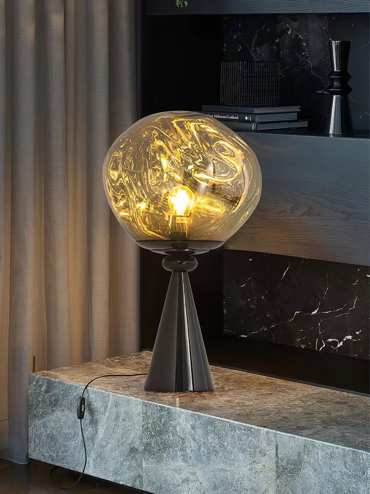 Glowing smoky globe on a black cone base on a stone cabinet, with a hanging cord switch