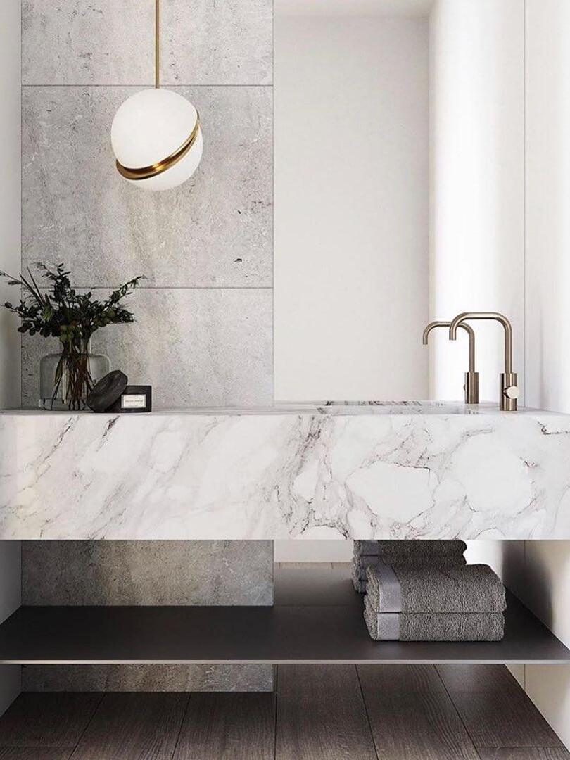 Single Crescent globe pendant beside a stone-look basin, faucet, towels and flowers