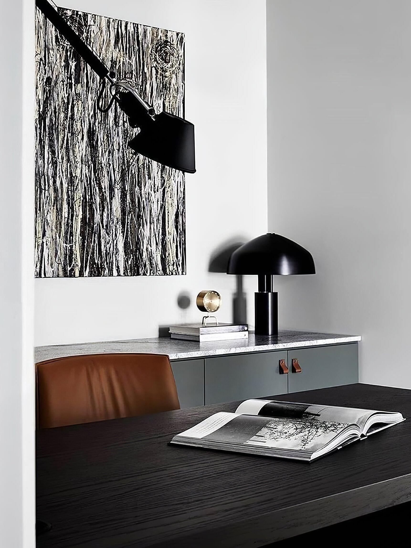 Black dome table lamp behind desk with open book