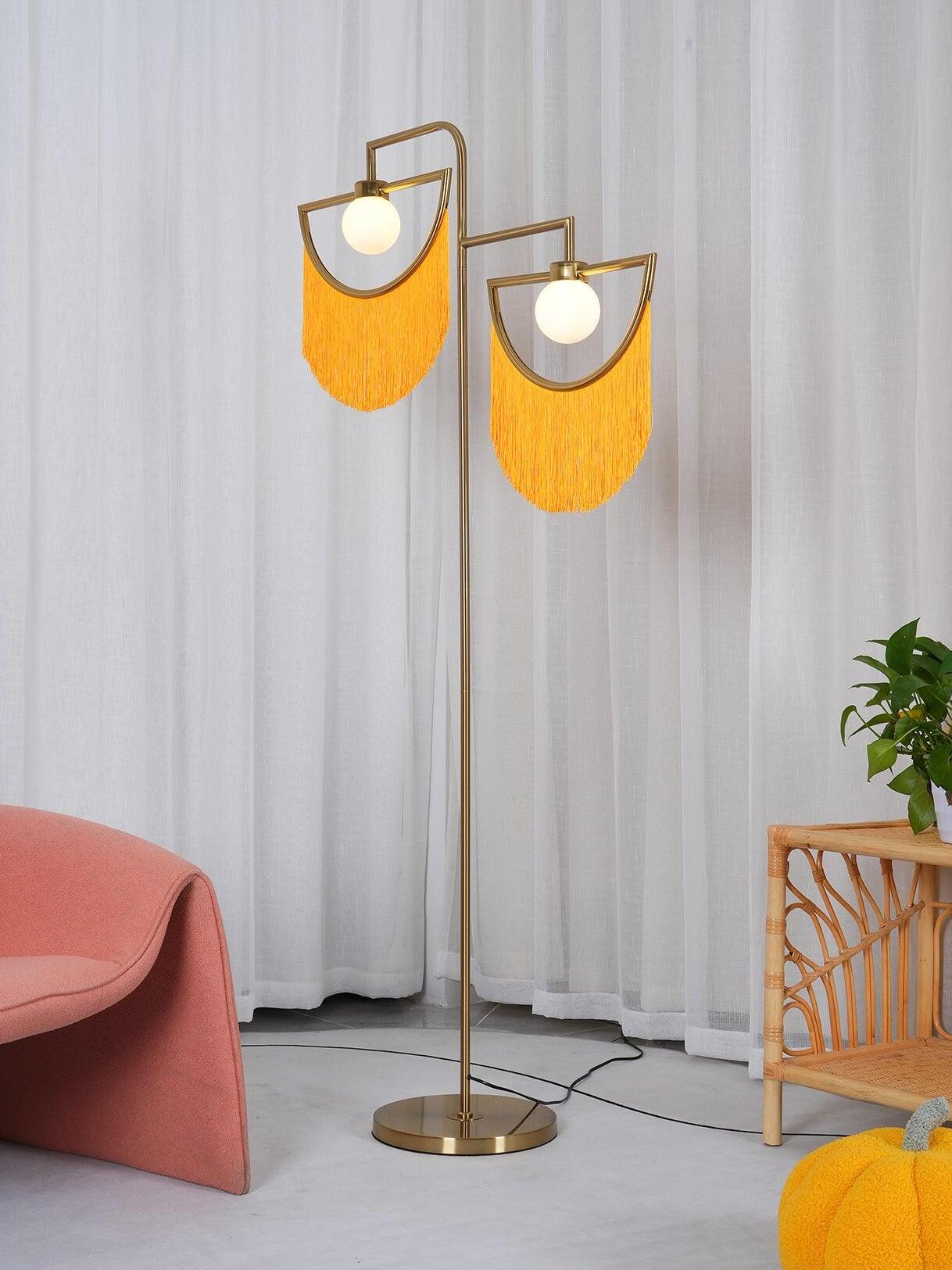 Wink floor lamp with yellow-orange fringes beside a pink chair