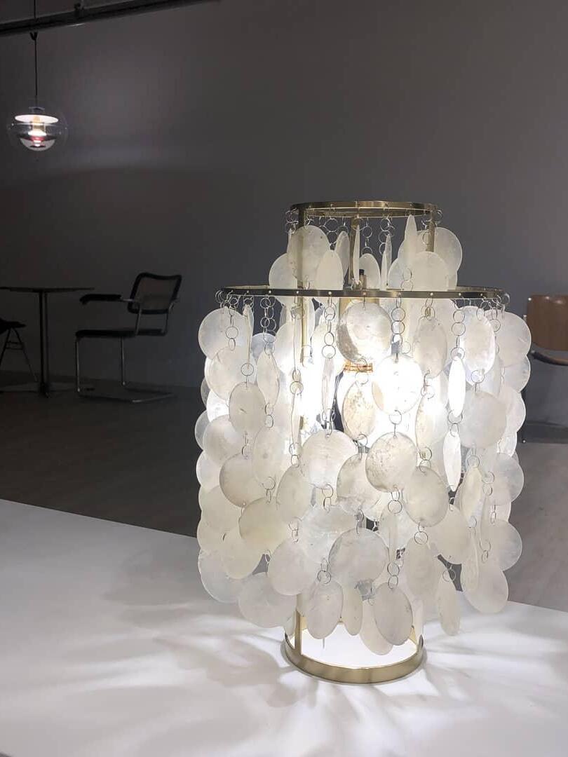 Illuminated shell table lamp on pale surface in dark room
