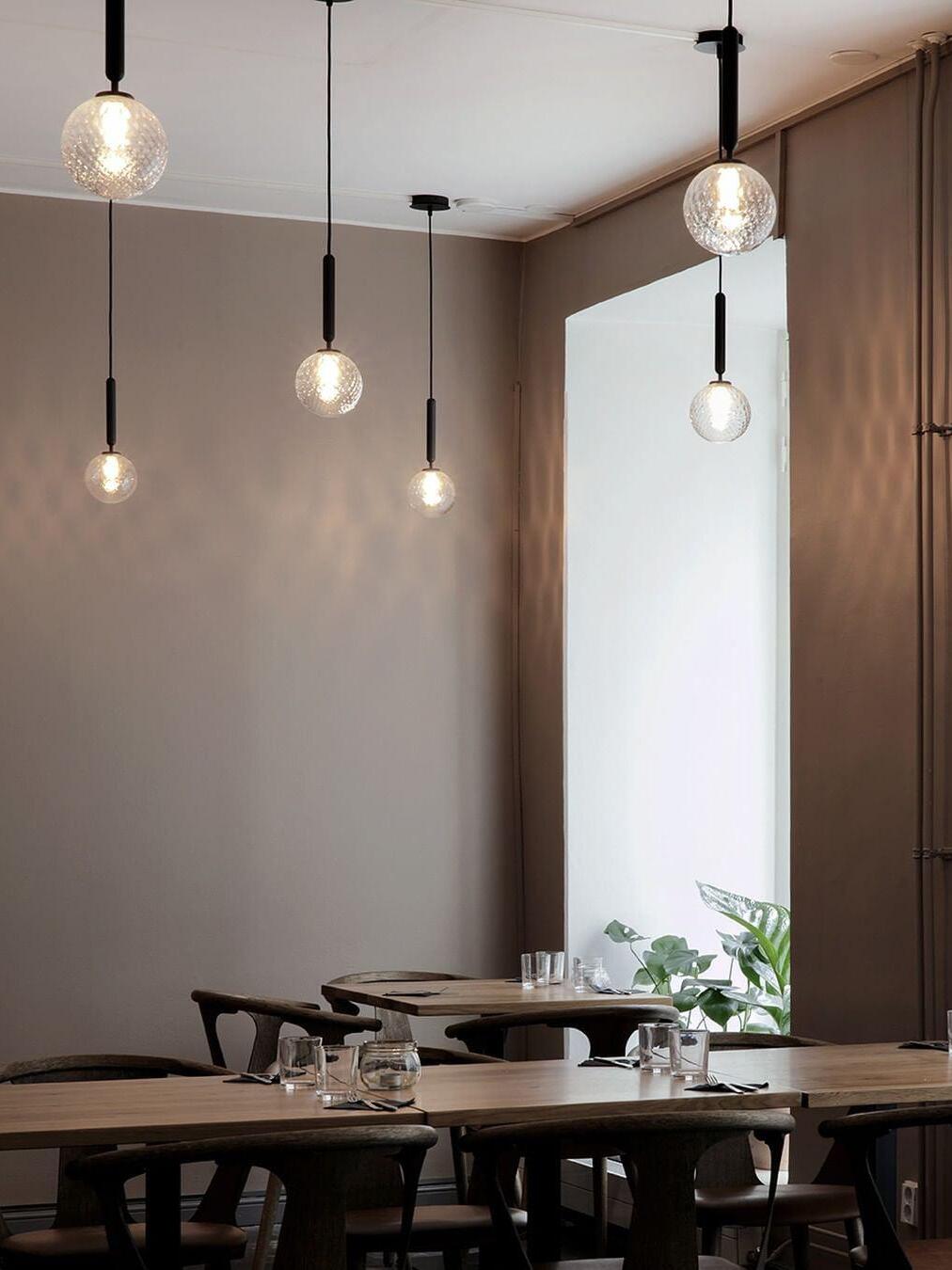 Multiple clear-globe pendants above a long dining table