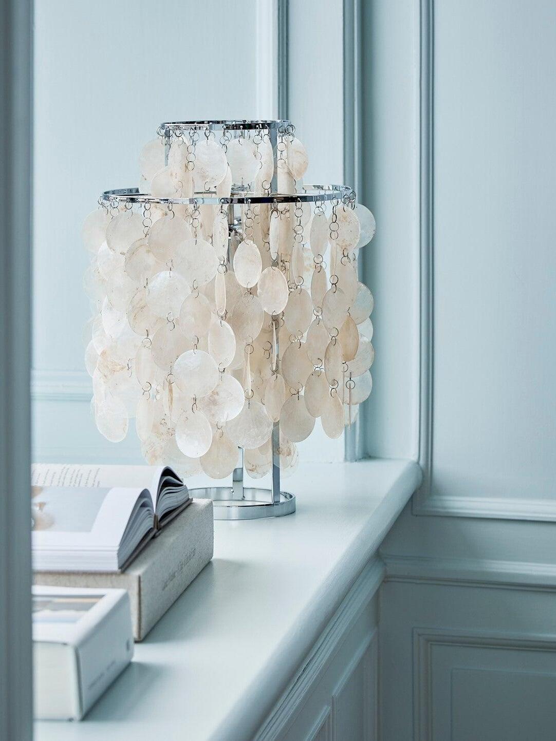 Shell table lamp on blue window ledge beside books