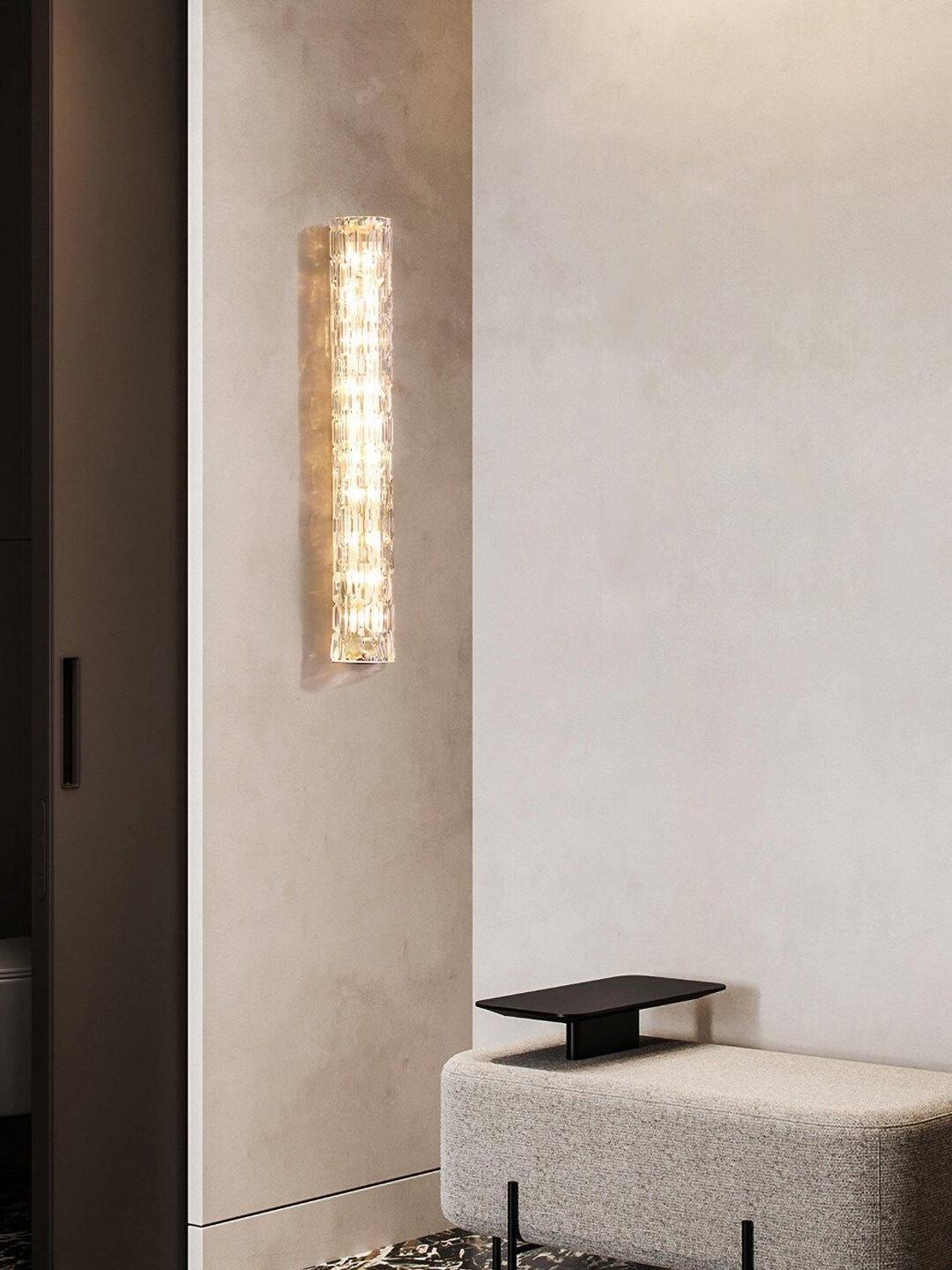 Vertical glass wall light beside basin and black tap