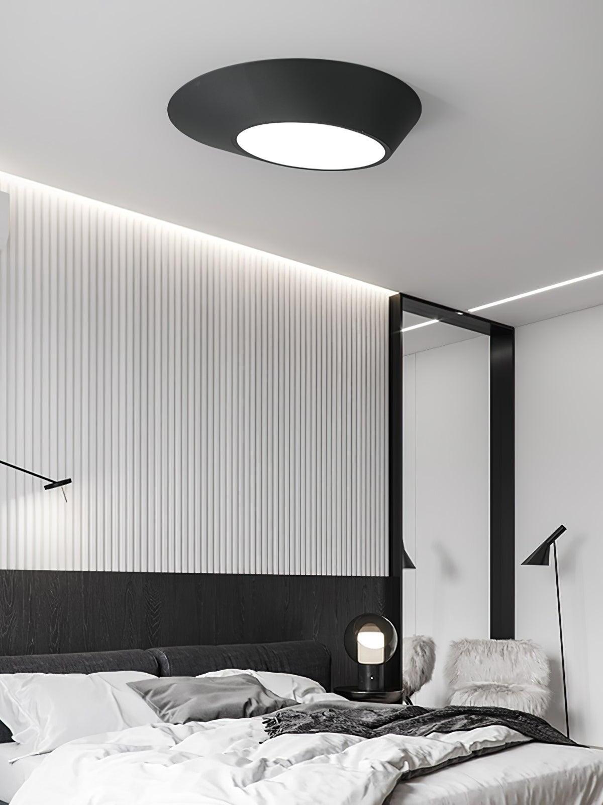 Black angled ceiling light above a monochrome bed beside white wall slats and other bedside lights