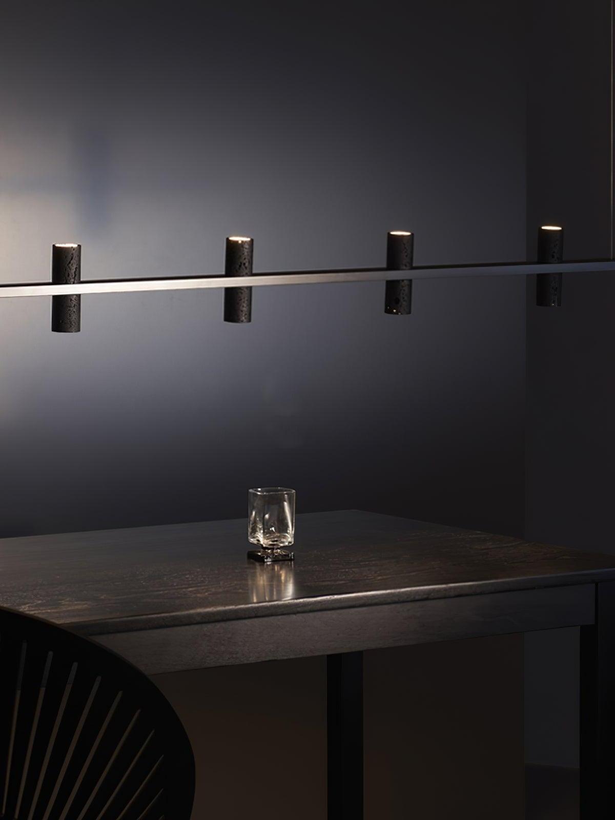 Black cylinder light above a dark dining table
