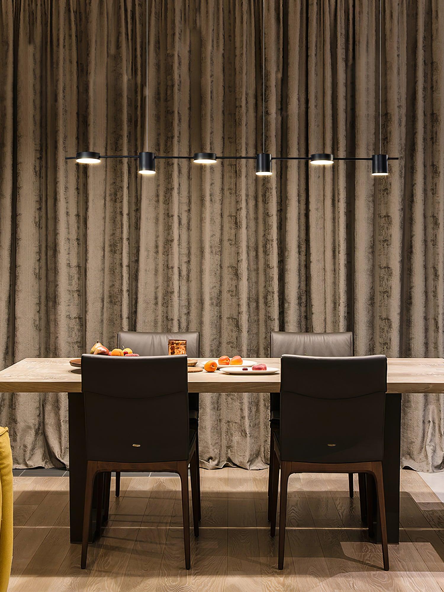 Slim black fixture above a dining table and dark chairs