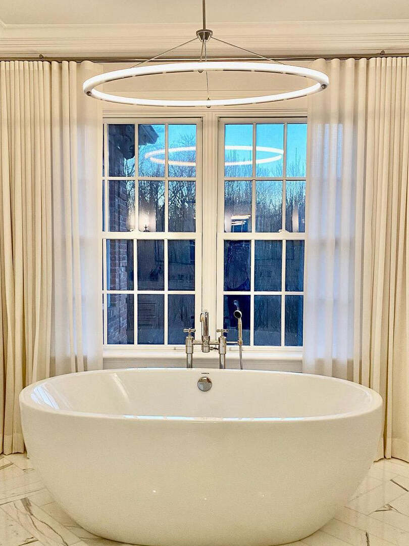 Suspended LED ring photographed above a freestanding bathtub