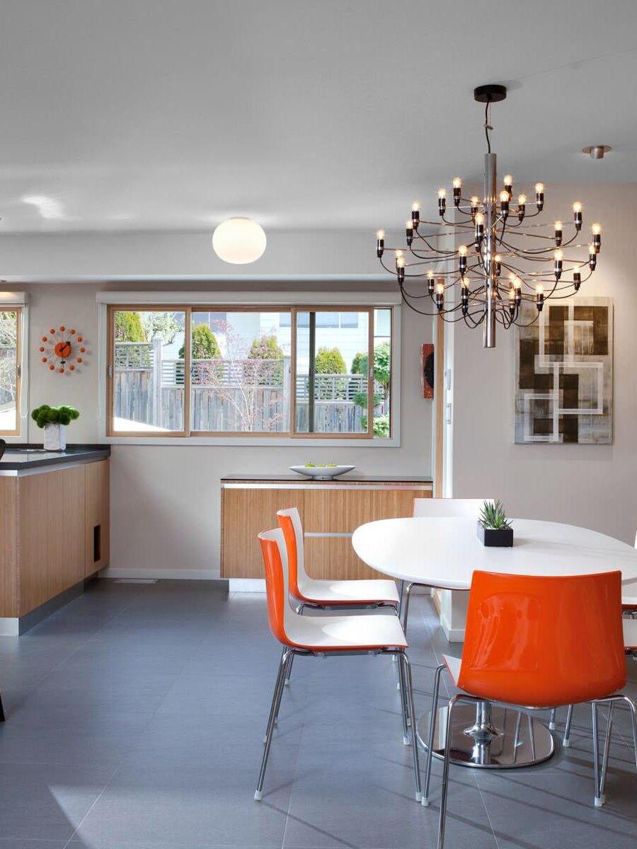 Exposed-bulb chandelier near orange dining chairs