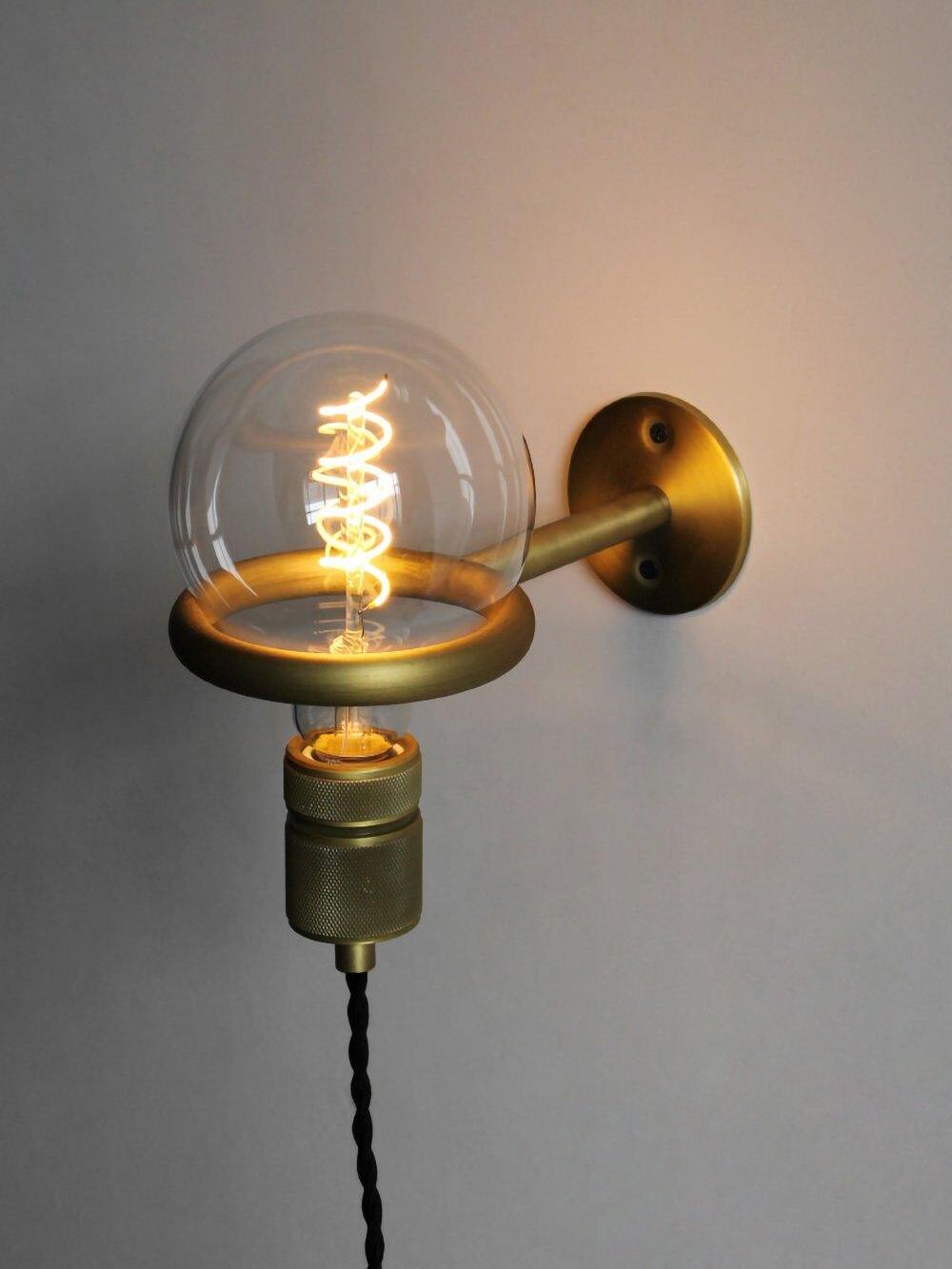 Lit globe bulb resting upward within loop wall bracket