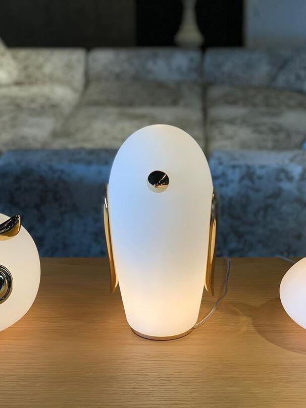 Tall glowing penguin on wood counter before brick wall