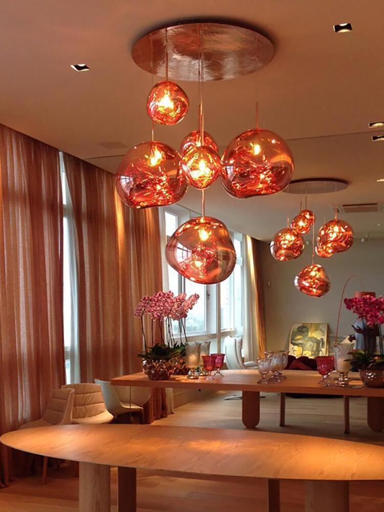 Warm-lit sculptural pendants above a dining table