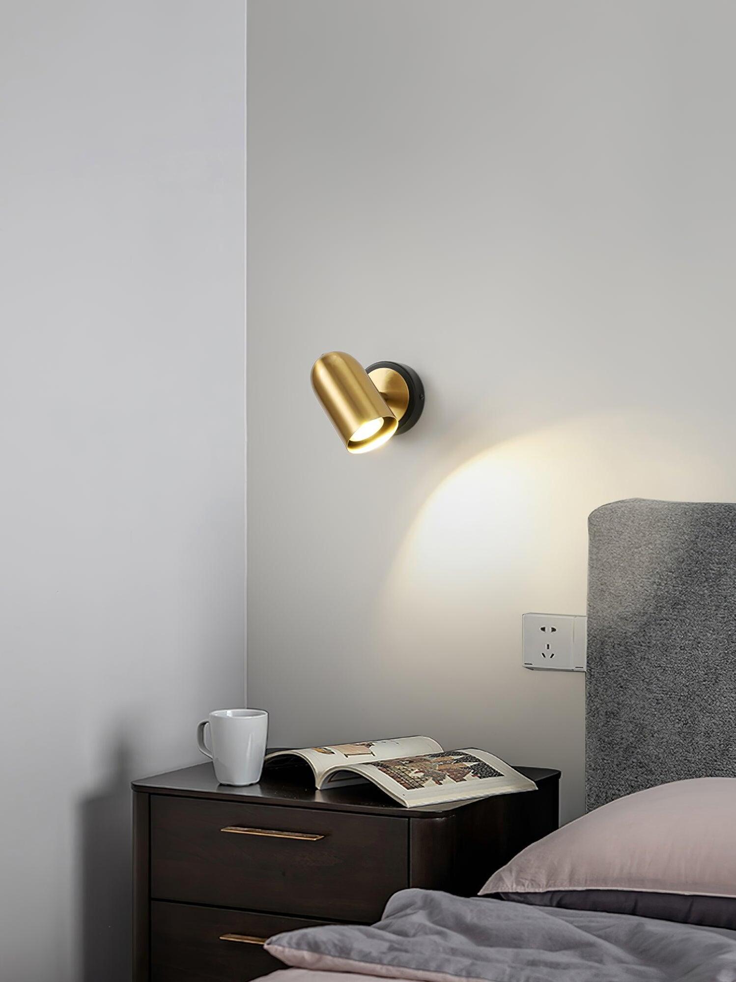 Single gold wall lamp over dark bedside table