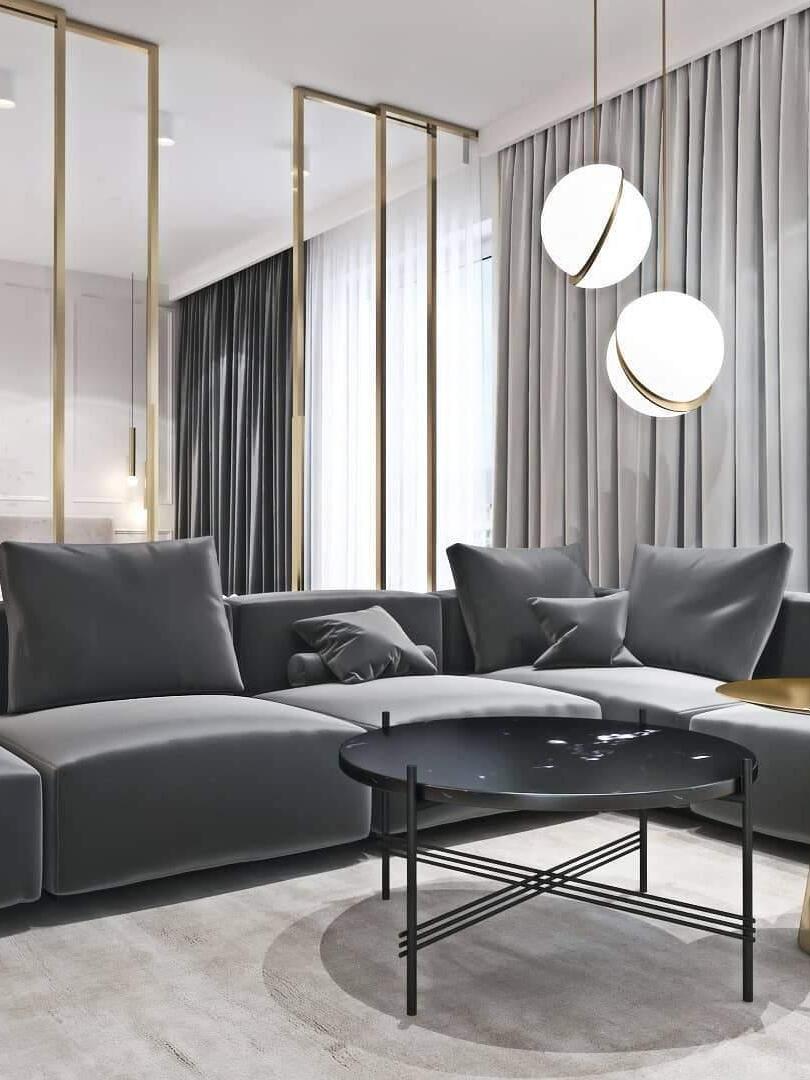 Two lit Crescent globe pendants above a grey sectional sofa beside curtains and mirrors