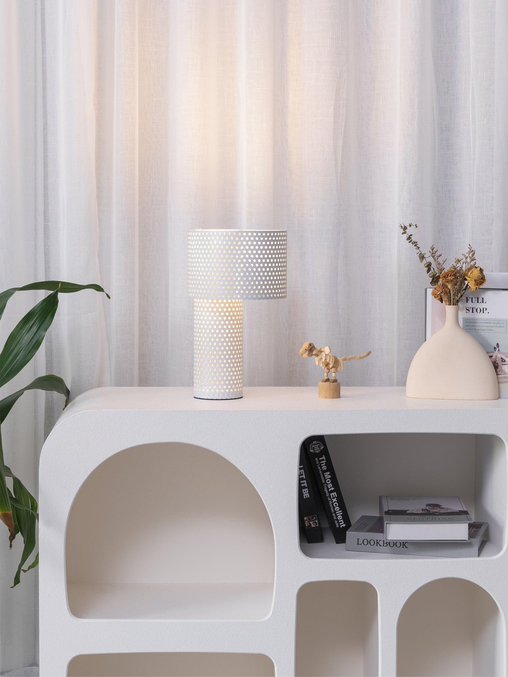 White perforated lamp on shelf beside flowers