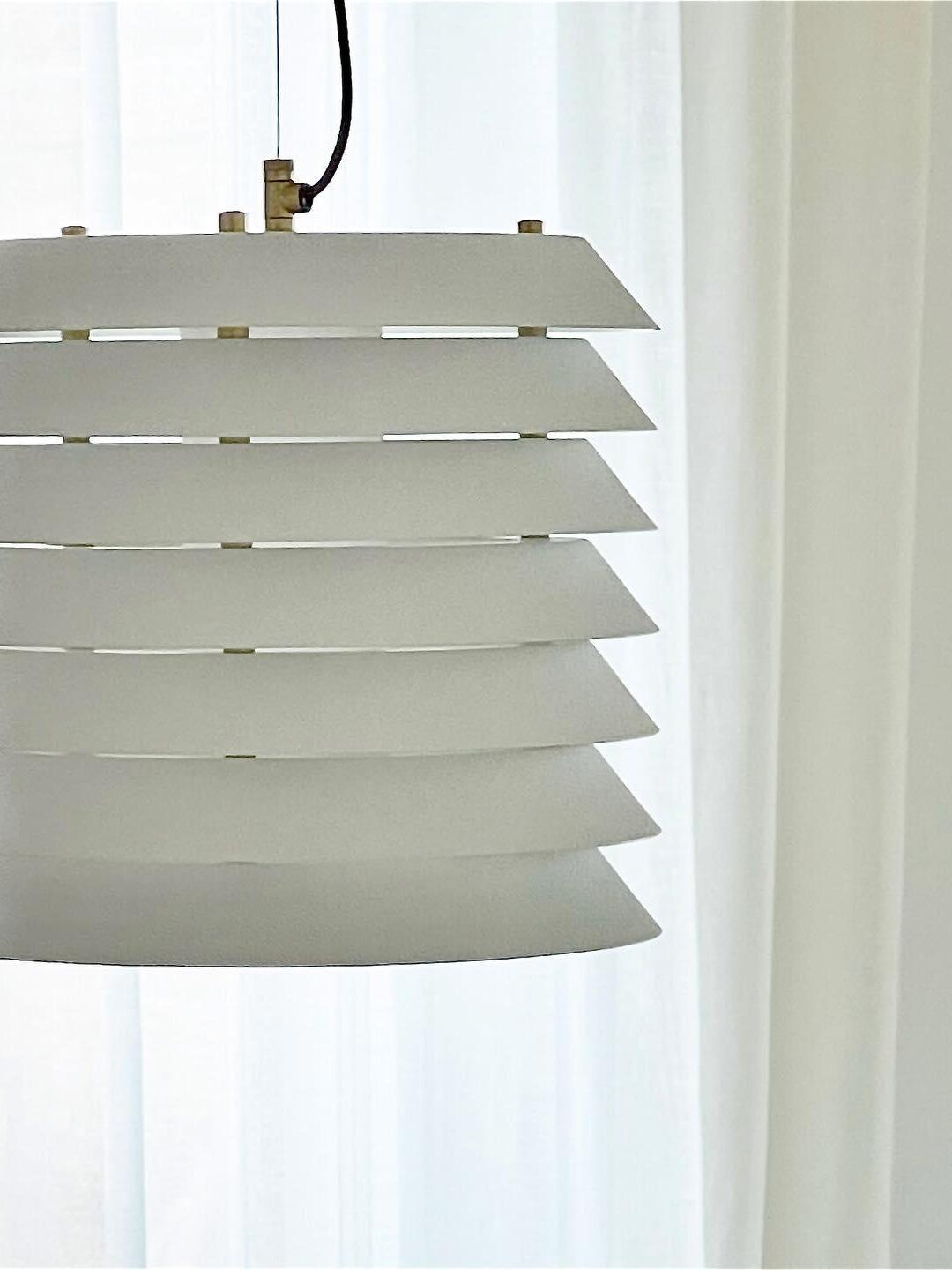 Close unlit white flared plates and spacer details against sheer curtains
