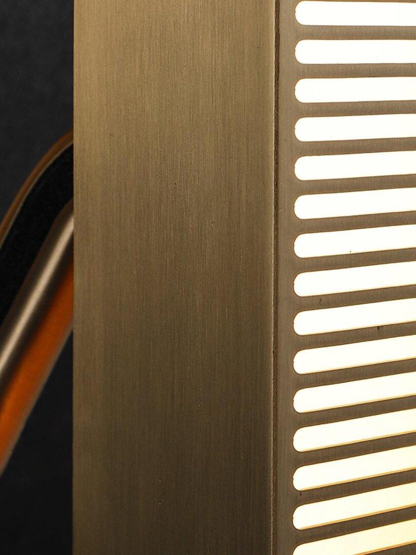 Close-up of gold-tone side face and glowing horizontal grille slots, with a dark-inset arm partly visible