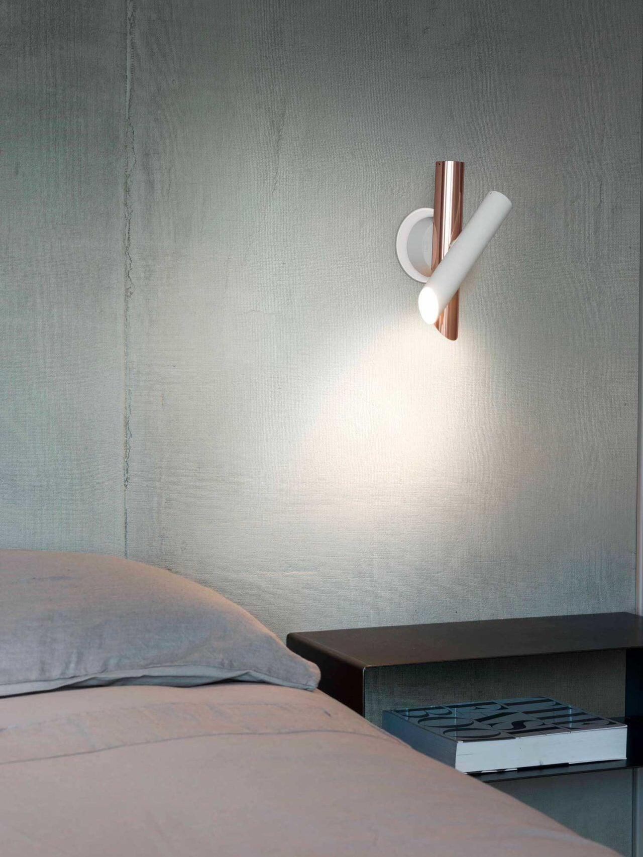 White and rose-gold wall light over bed