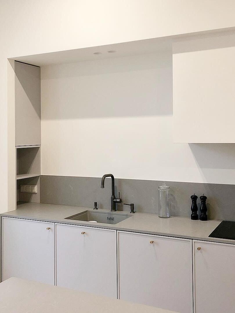 White kitchen cabinets and grey worktop with stainless sink, black tap and hob edge