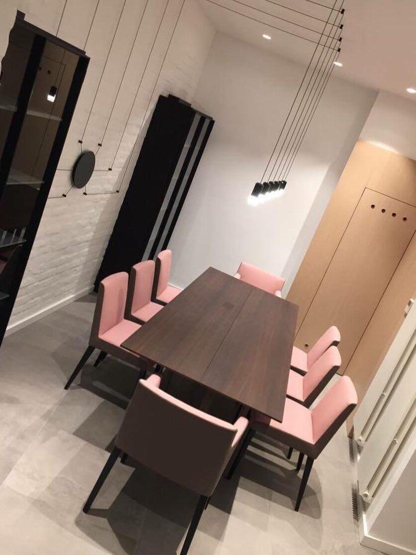 Ceiling-routed cable pendants above a dark rectangular table and pink chairs