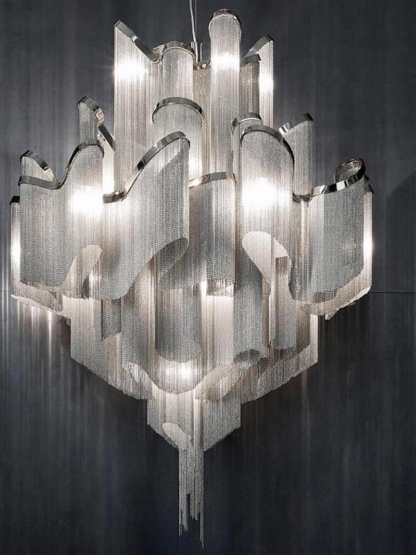 Silver-coloured chandelier with illuminated chain fringe cascading from wavy tiers
