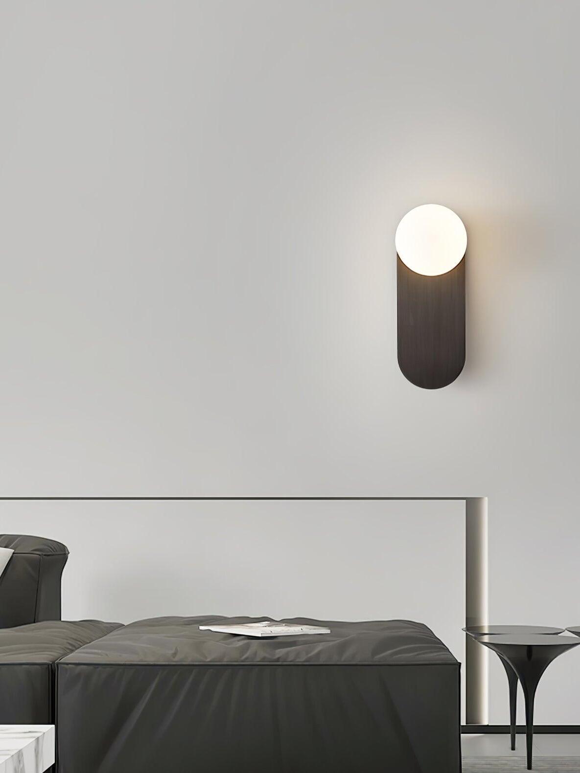 Single globe sconce on a bedroom wall above a bed