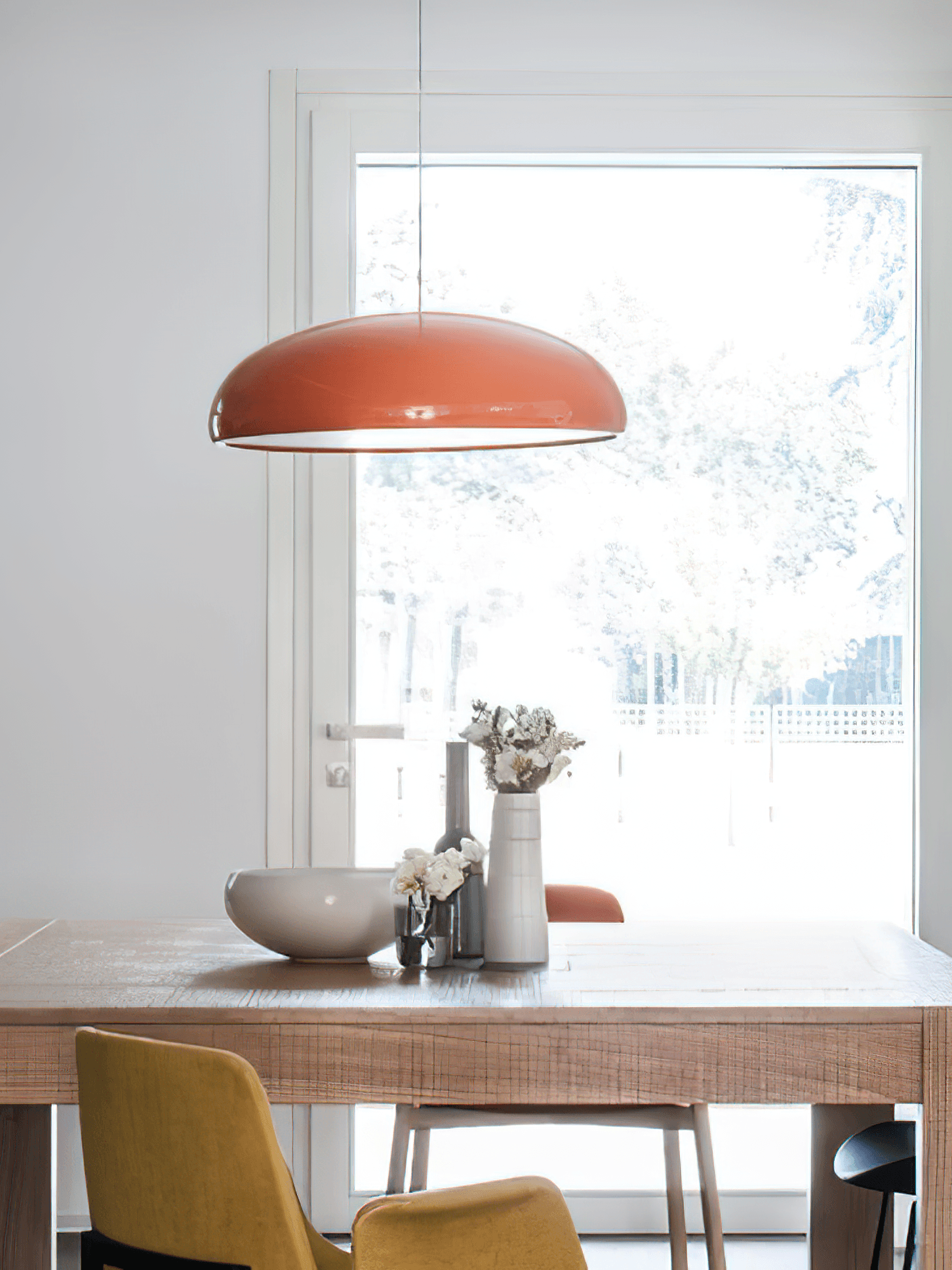 Orange dome pendant over a wooden dining table