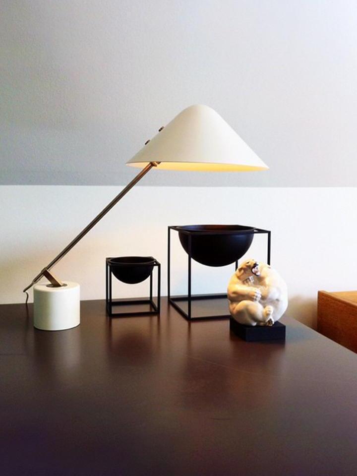 Lit white desk lamp beside black display stands on a dark table