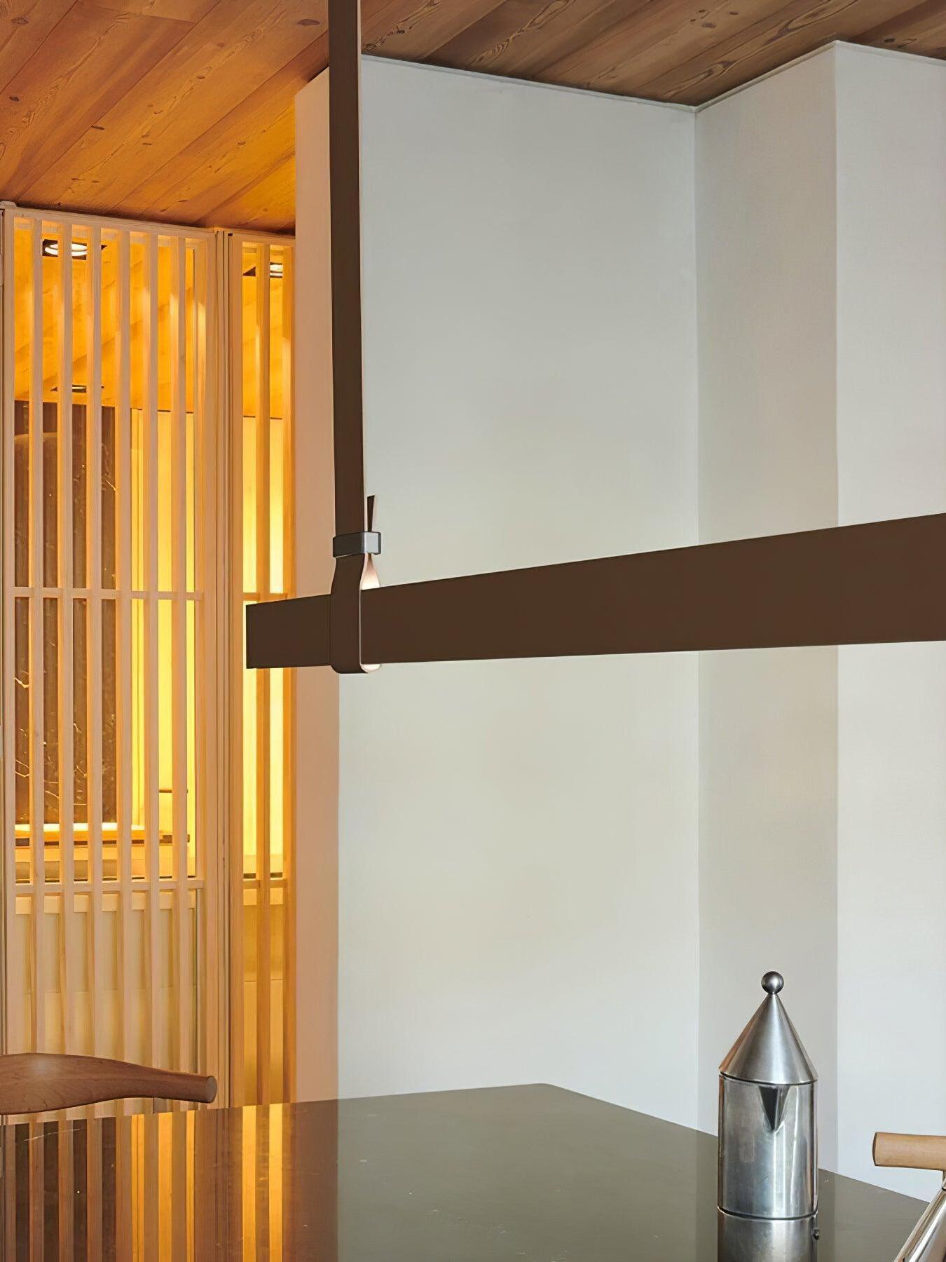 Brown strap loop and silver-tone connector around the horizontal bar, with a wood ceiling and slat partition behind