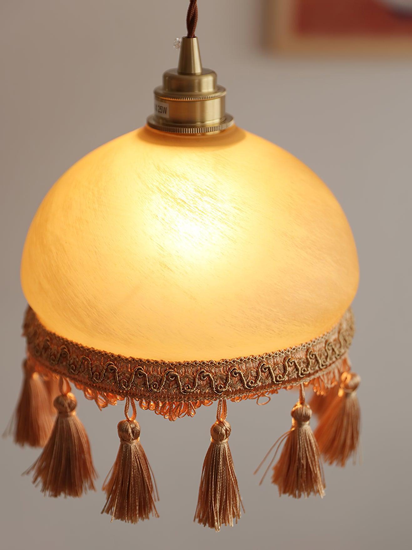 Close lit yellow shade with brass-toned top and tassels
