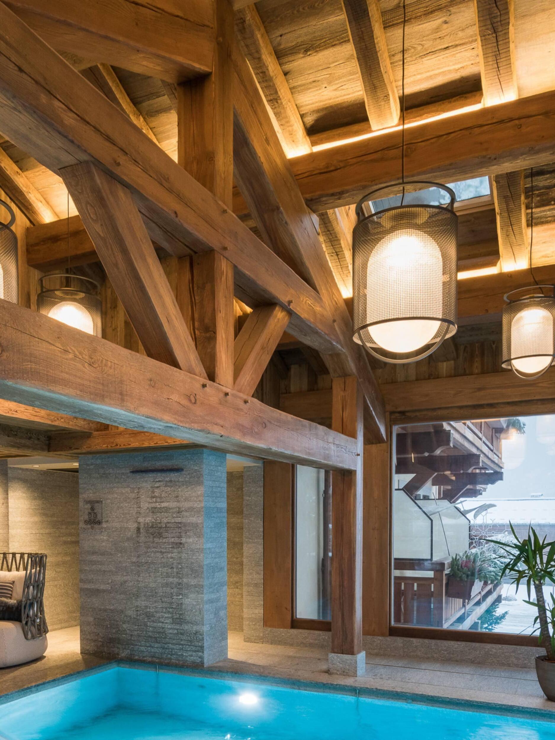 Black lantern pendants suspended over timber-framed pool area