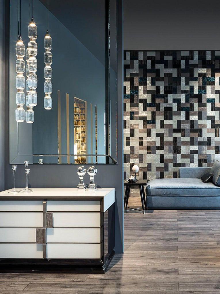 Three slim stacked glass pendants near a blue wall