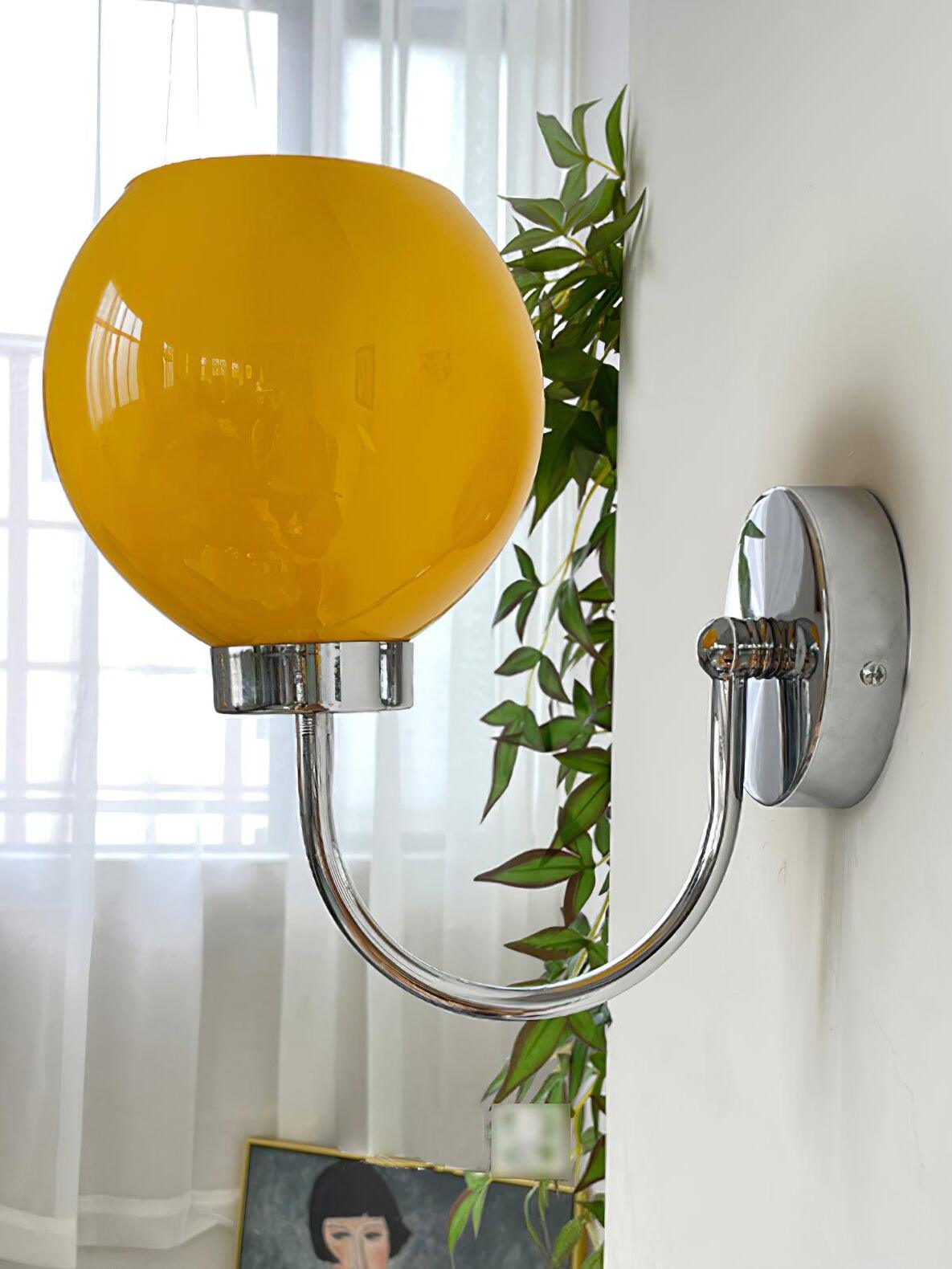 Close orange globe above curved silver-tone arm and circular plate beside plant