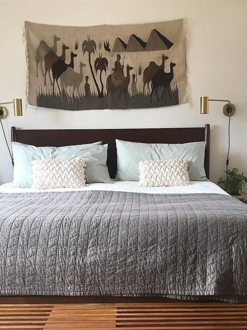 Two brass-tone wall lights beside bed beneath wall art