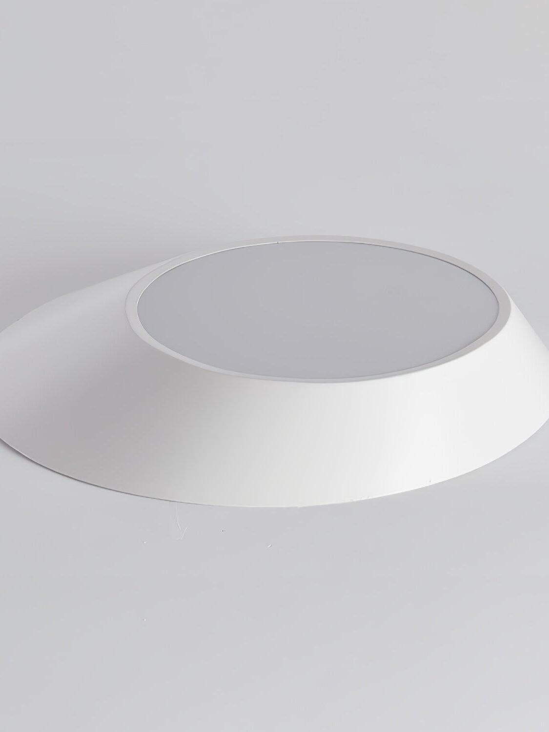 White angled ceiling light resting upside down with its round diffuser unlit