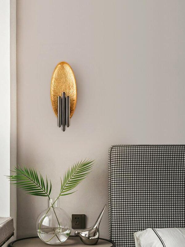 Wide view of oval sconce above plant vase and side table near chair
