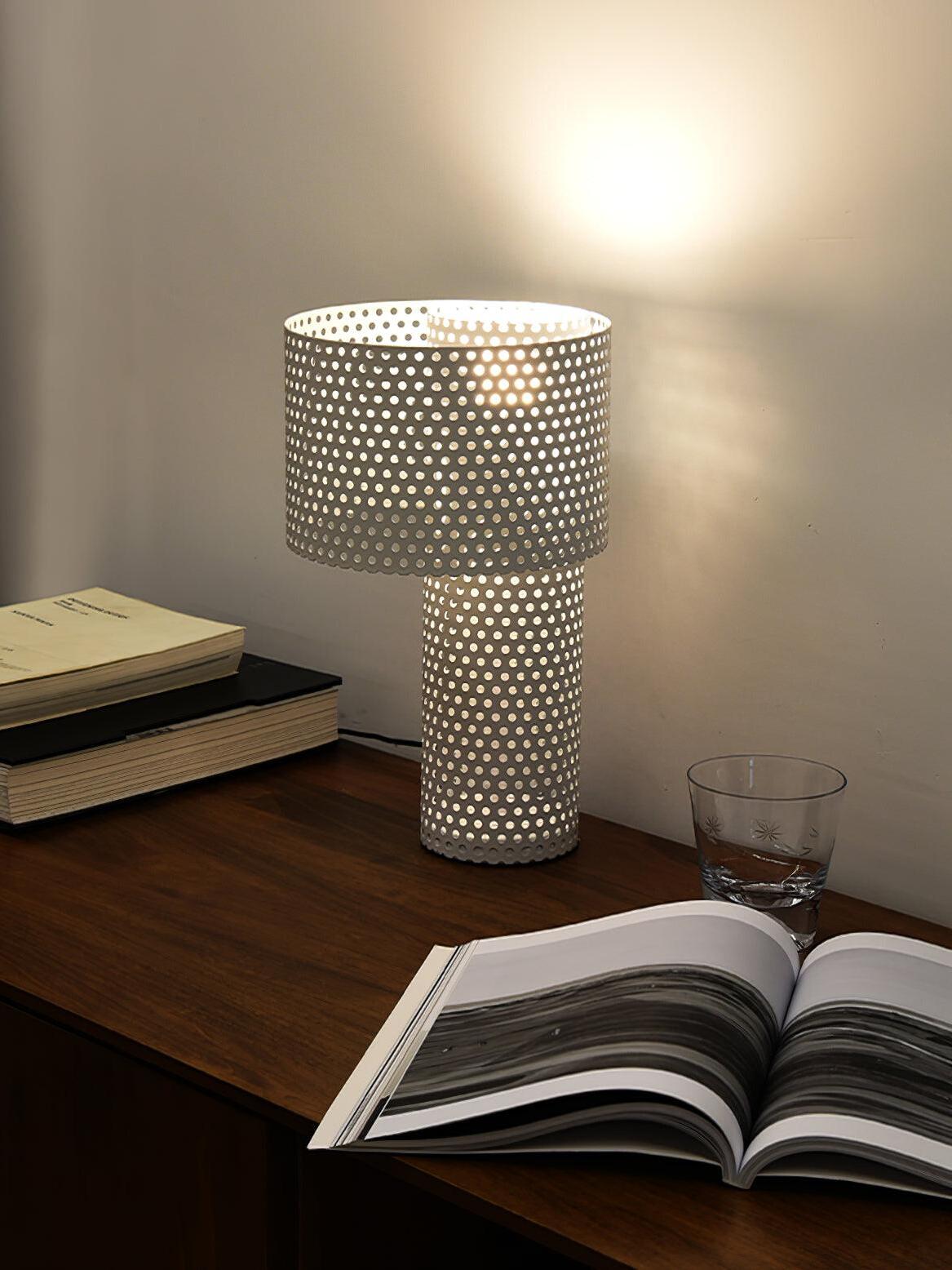 Lit white table lamp beside open book