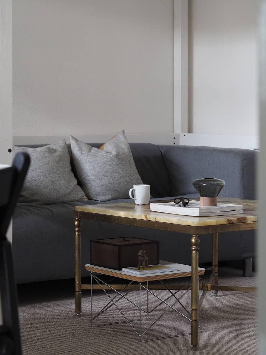 Small smoky table lamp on books on wood coffee table before grey sofa