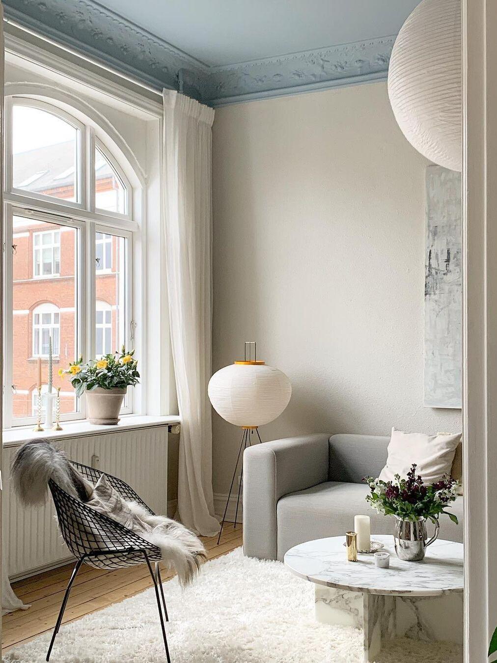 Round floor lamp beside seat near windows