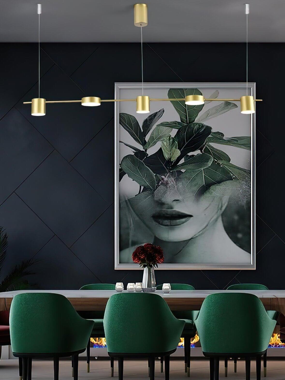 Gold disc-and-cylinder light above green dining chairs