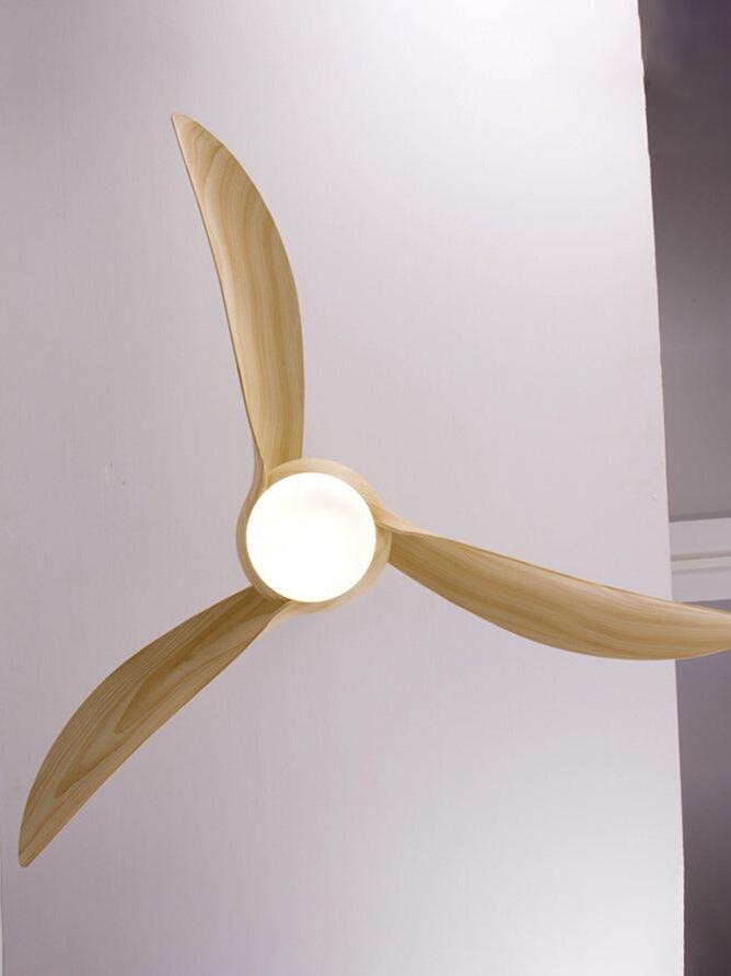 Underside view of three pale woodgrain-looking blades surrounding a bright circular light near a ceiling edge