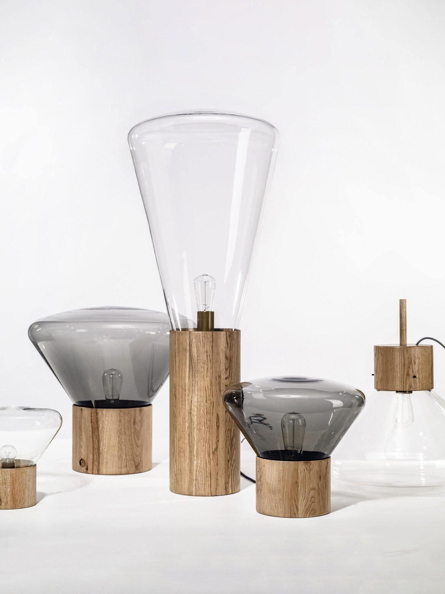 Broad glass lamps and tall narrow glass form with wood bases in family display