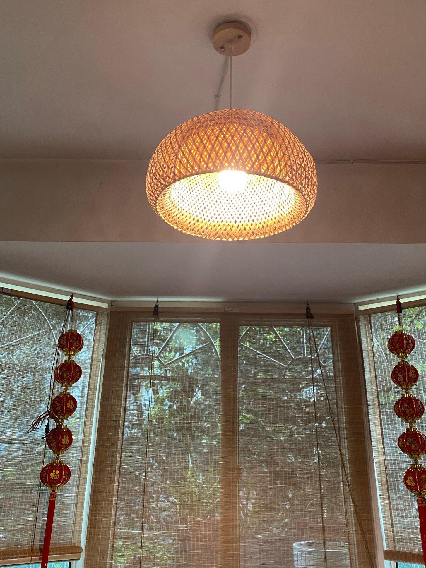 Lit bamboo pendant below ceiling plate near curtained windows