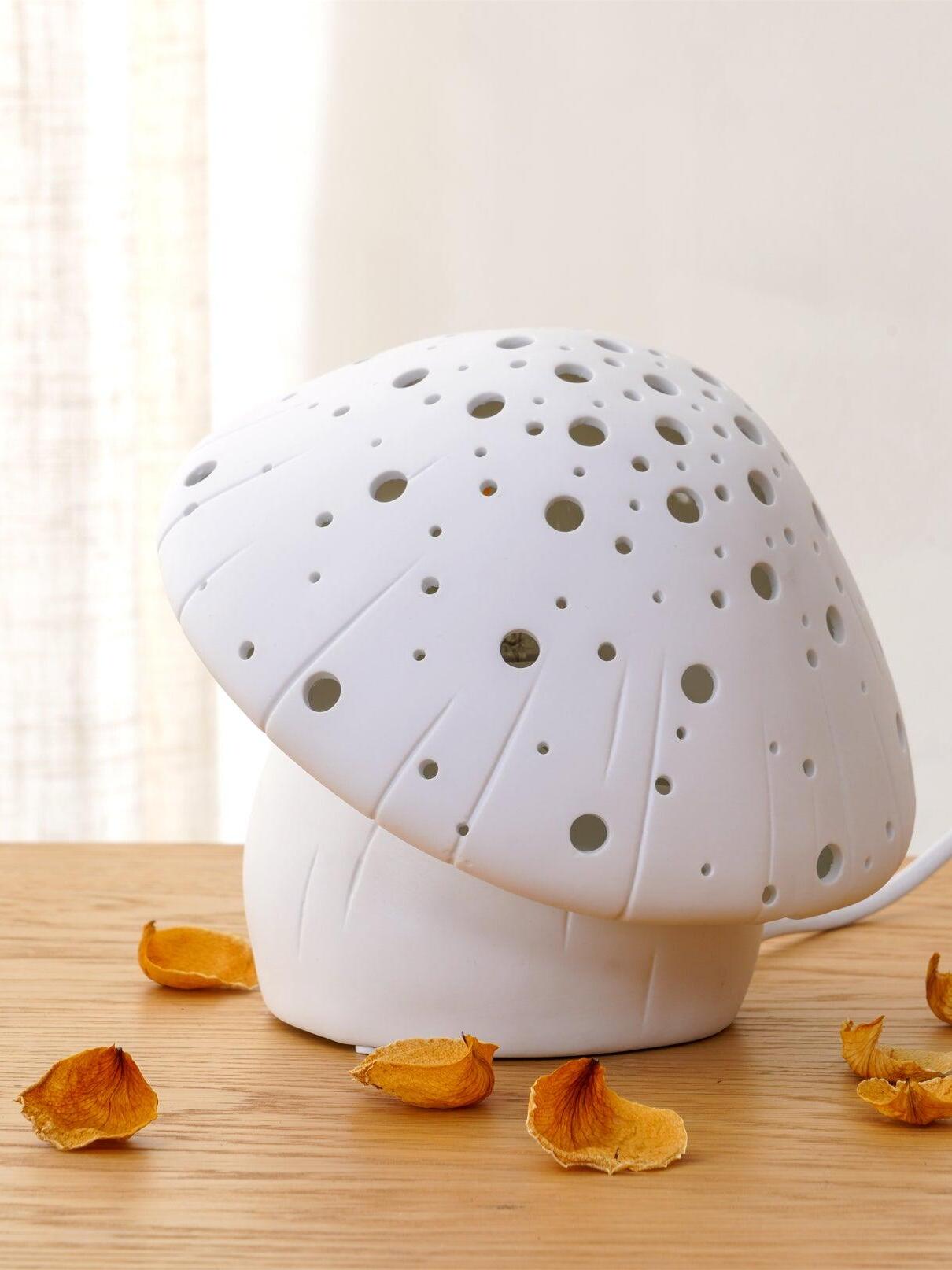 Closer unlit view of the white perforated cap and grooved base beside petals and a curtain