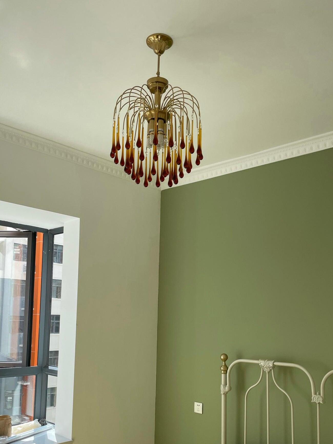 Small chandelier against a green interior wall