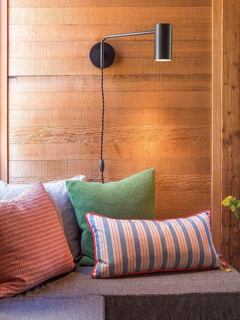Black wall light on wood panels beside sofa cushions